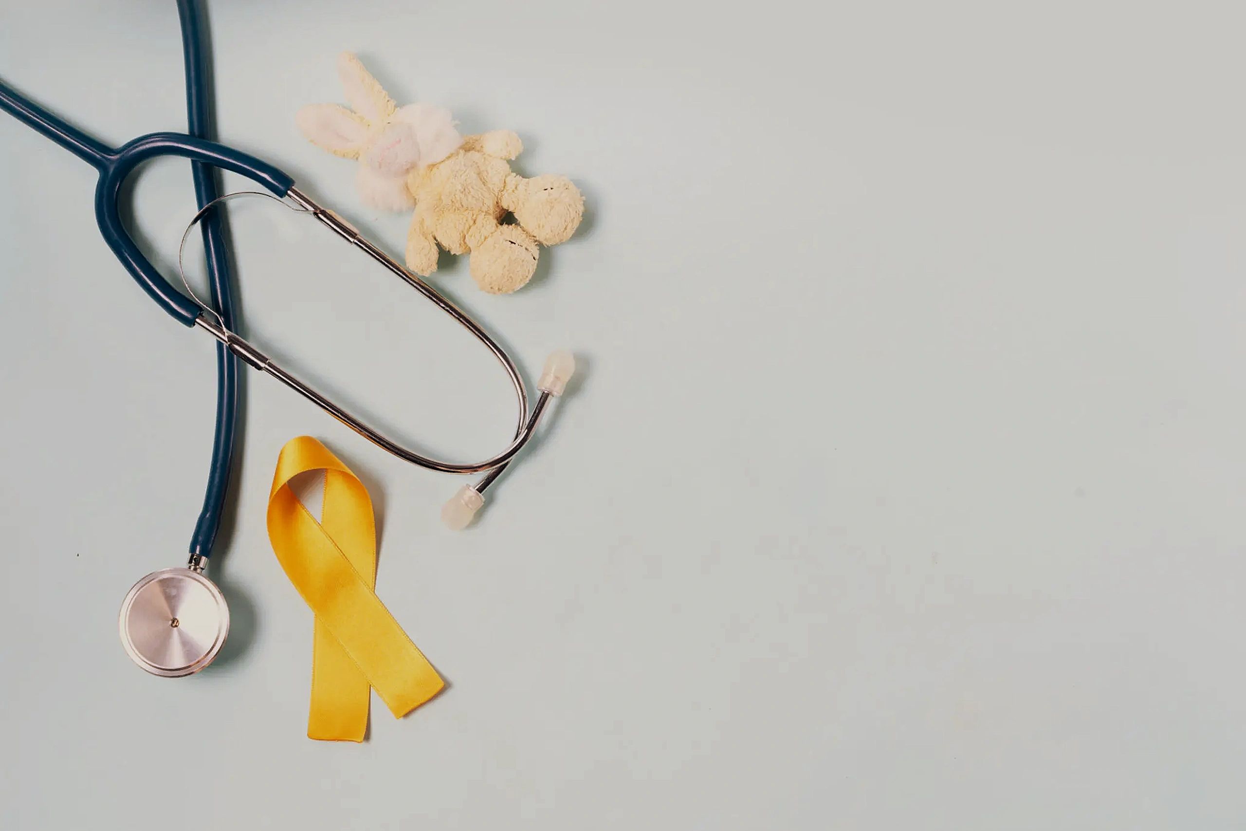 Stethoscope and yellow awareness ribbon health flat lay